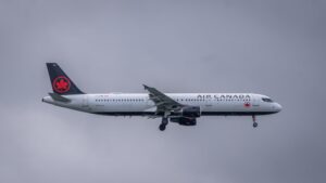 Air Canada aircraft landing with landing gear extended against cloudy skies